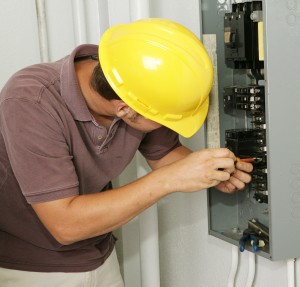 An electrician working on an electrical breaker panel. Model is an actual electrician - all work is being performed according to industry codes and safety standards.