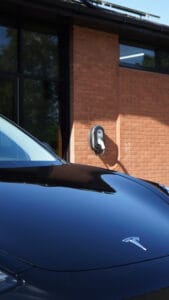 tesla vehicle parked in front of wall charger mounted on side of home